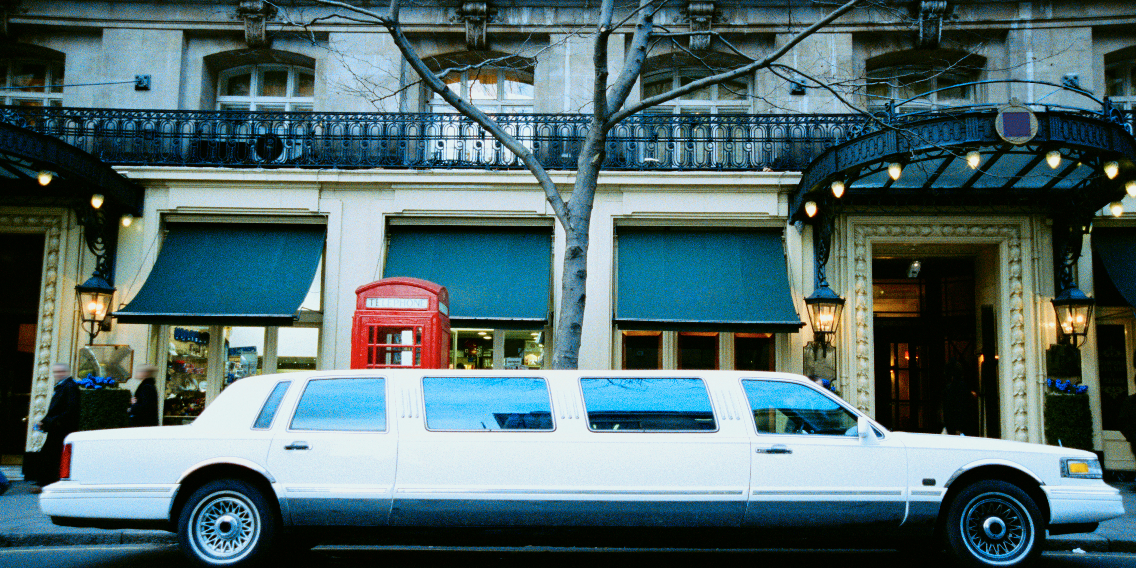White stretch limousine parked outside a luxury hotel.