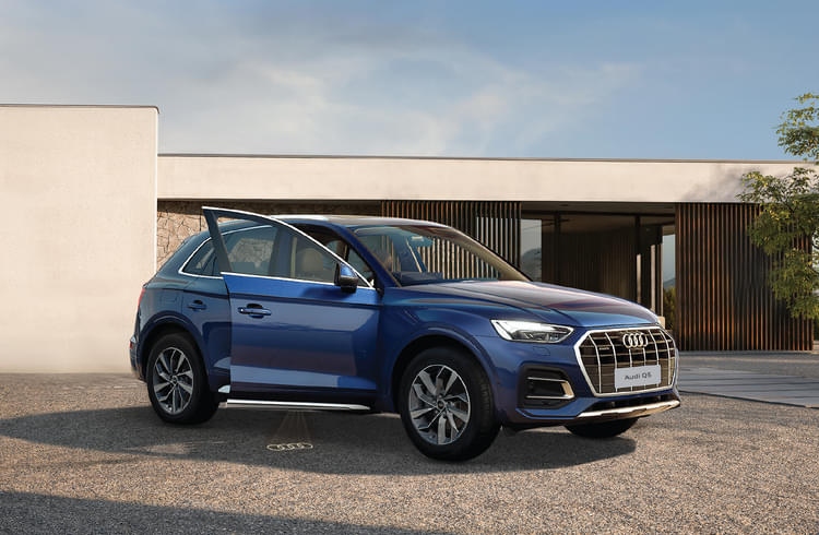 Blue luxury Audi Q3 SUV parked outdoors with the driver-side door open.