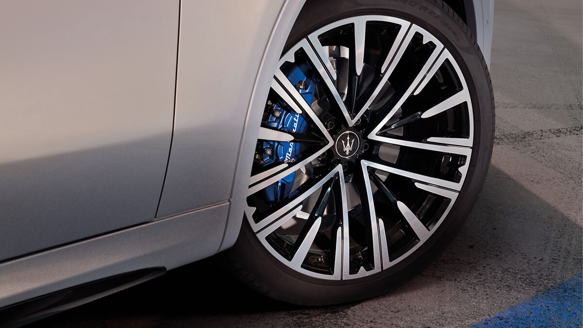 Maserati luxury alloy wheel with black and silver spokes and blue performance brake caliper on a premium SUV.