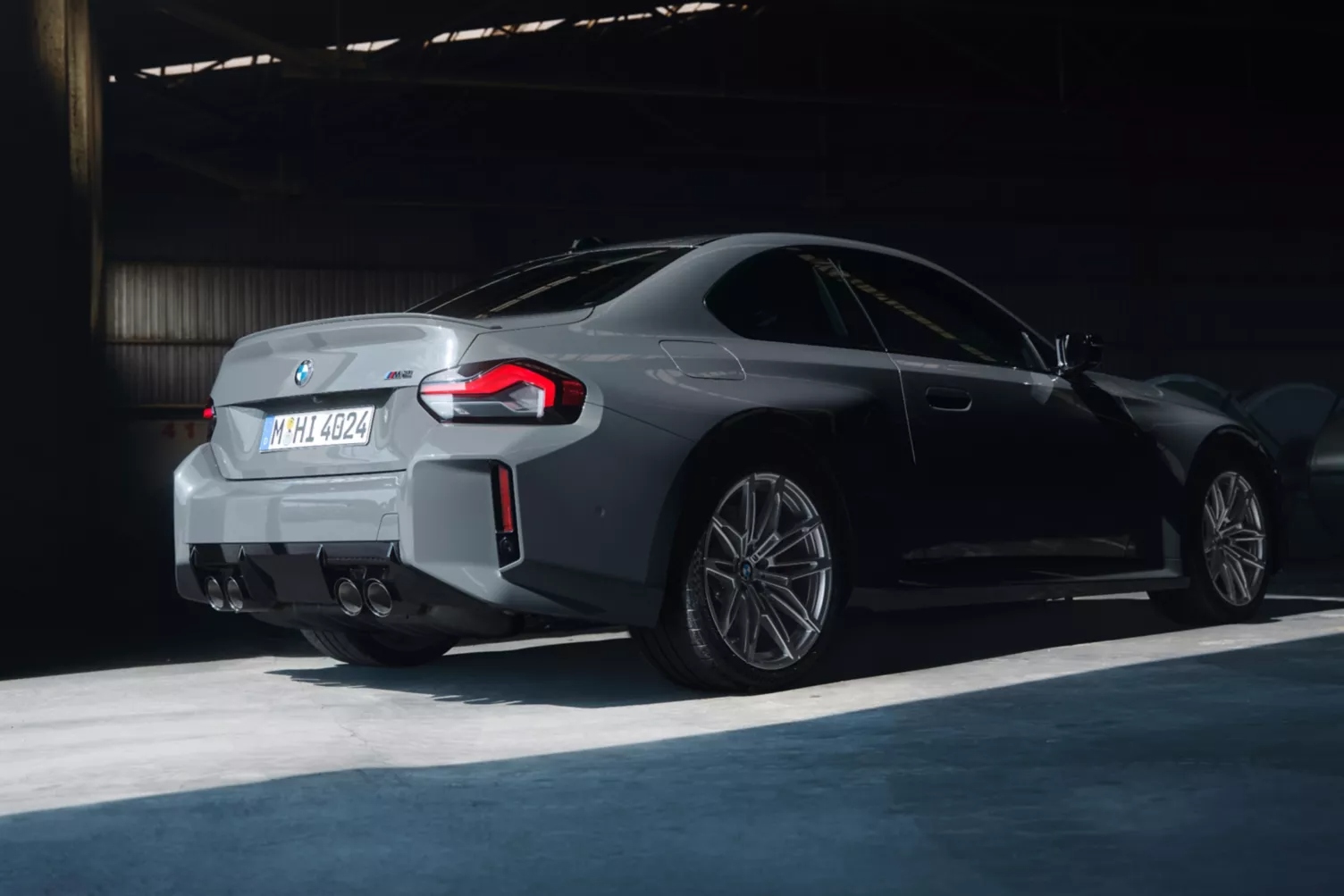 BMW M2 Coupe rear three-quarter view in grey showcasing quad exhausts, LED tail-lights, and sporty stance.