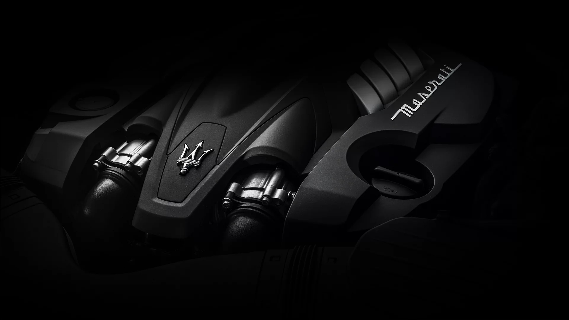 Maserati high-performance engine close-up featuring the iconic trident logo and signature engine cover design.