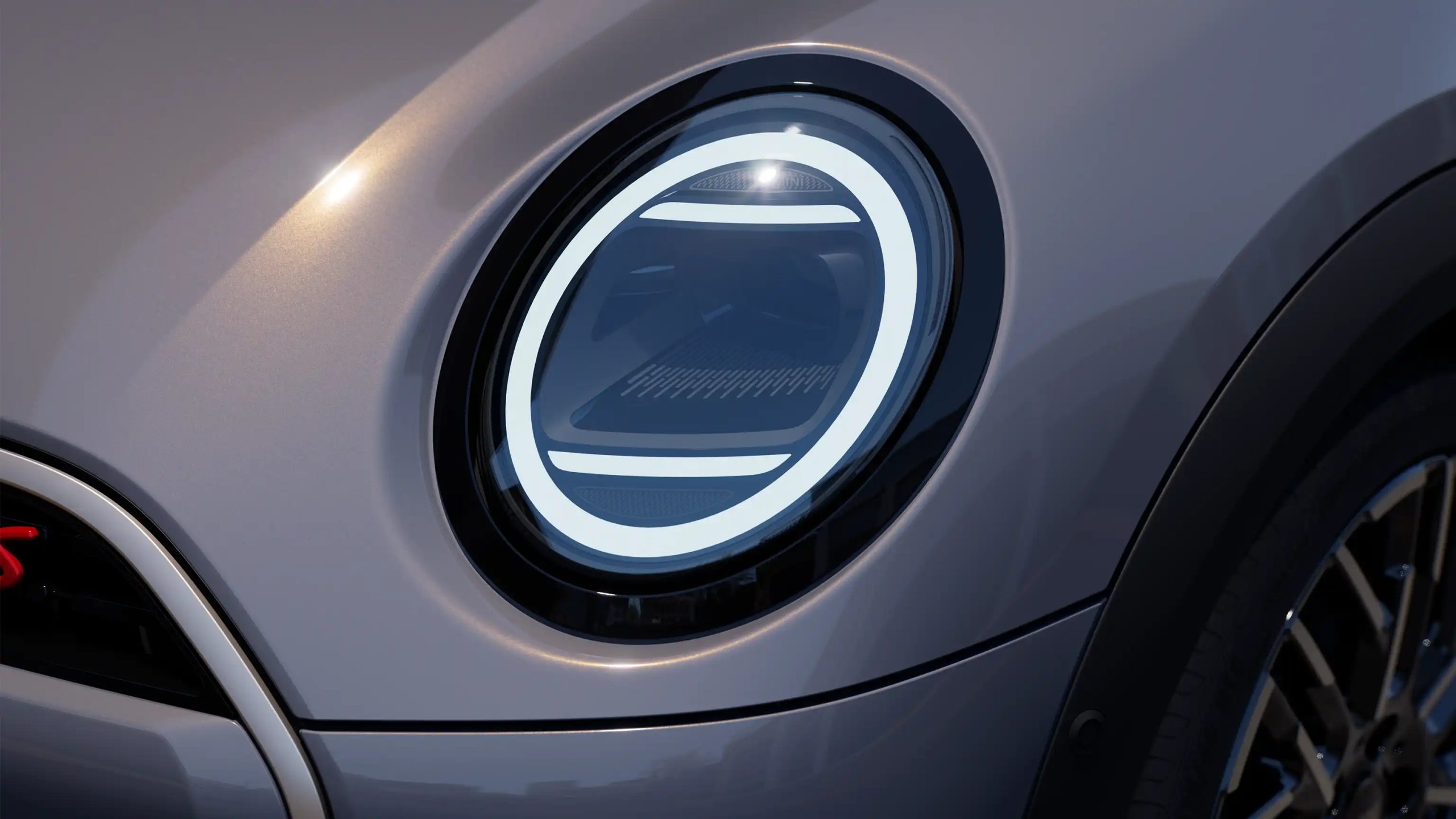 2025 MINI Convertible LED circular headlight close-up showcasing modern DRL ring design and smooth grey bodywork.