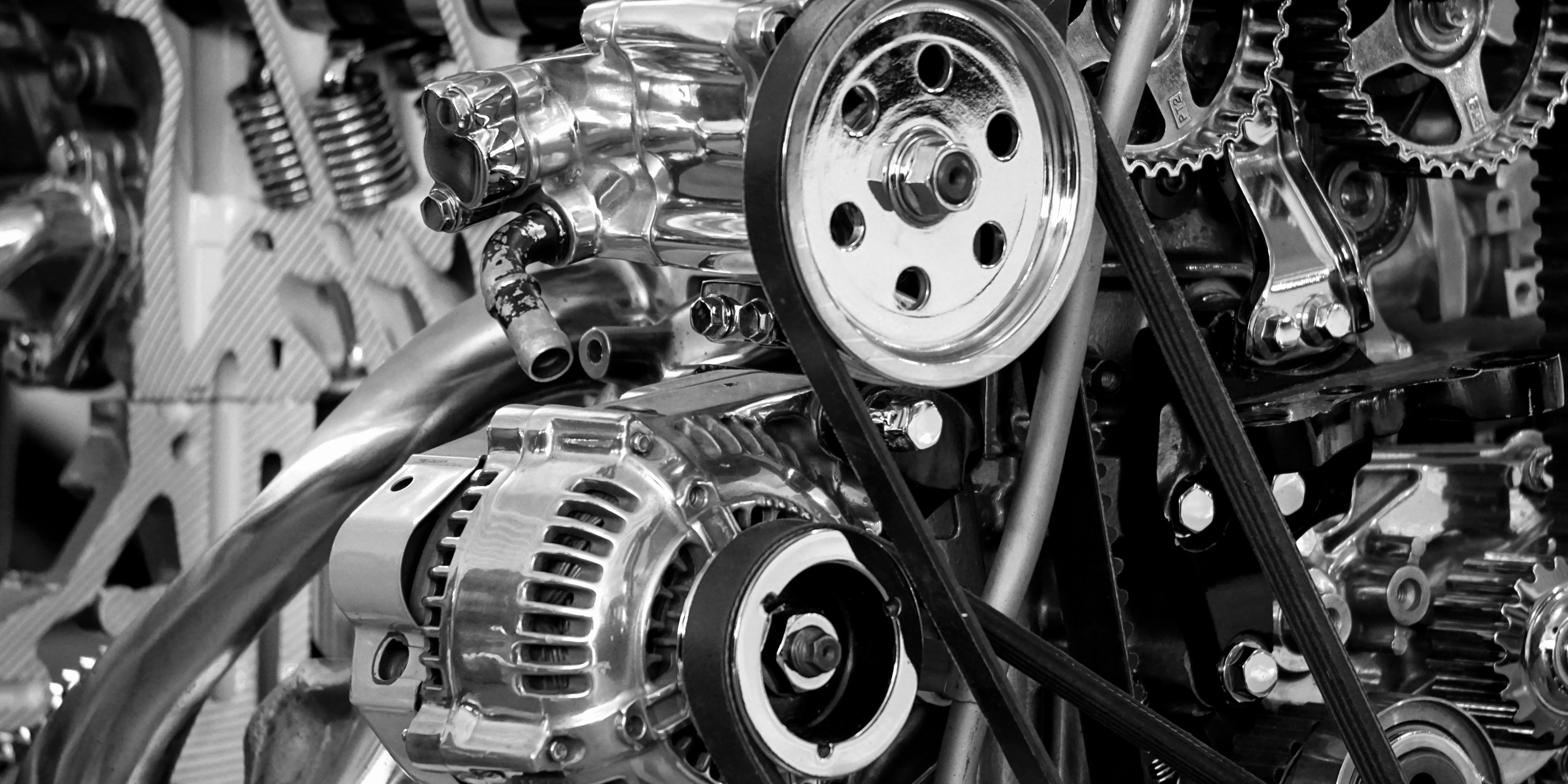 Close-up view of a car engine with metallic components, belts, and gears.