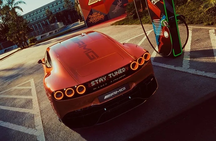 Rear view of orange Mercedes-AMG electric car parked at charging station with futuristic taillights.